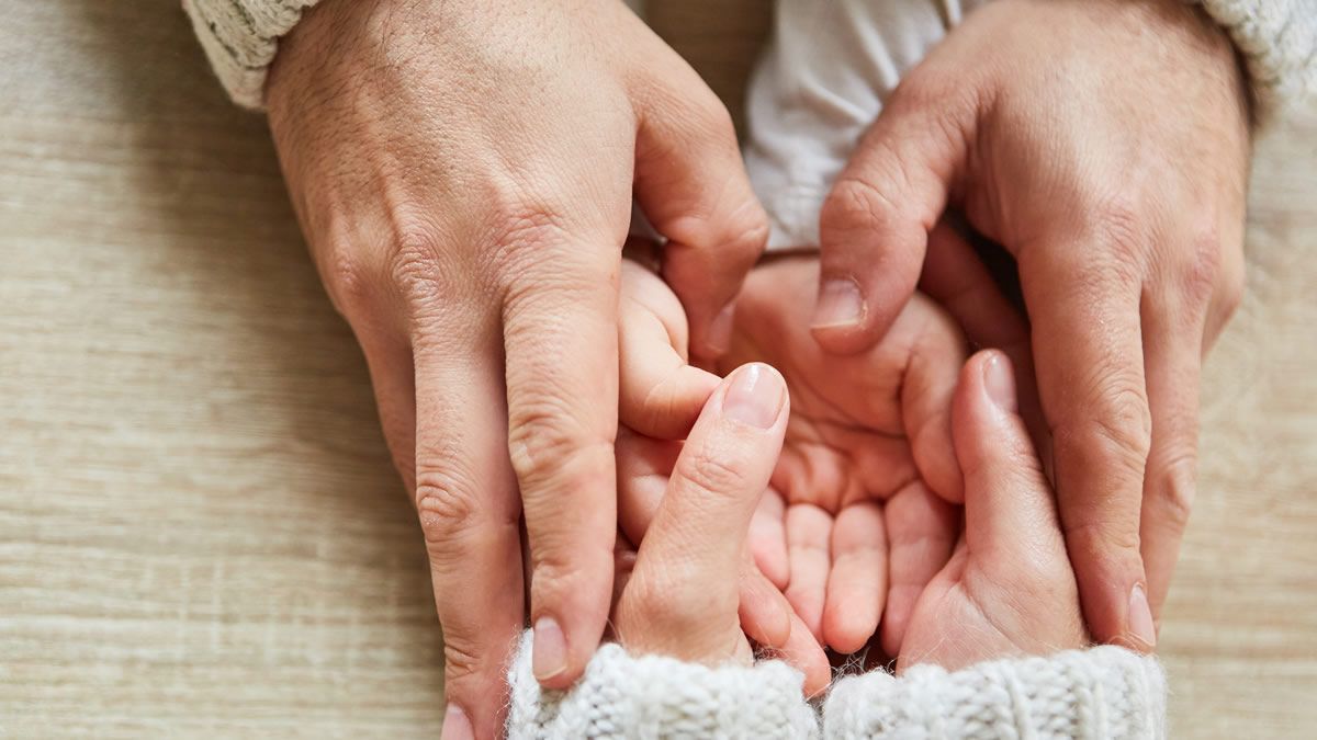 close up of adult's hands holding child's hands