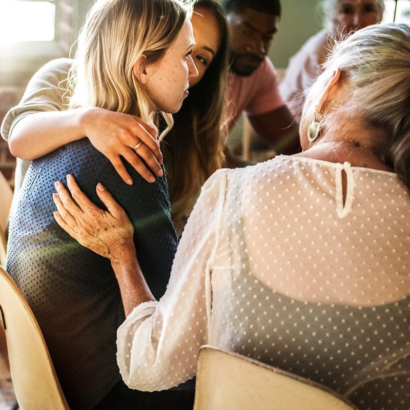women comforting a young woman in a group setting