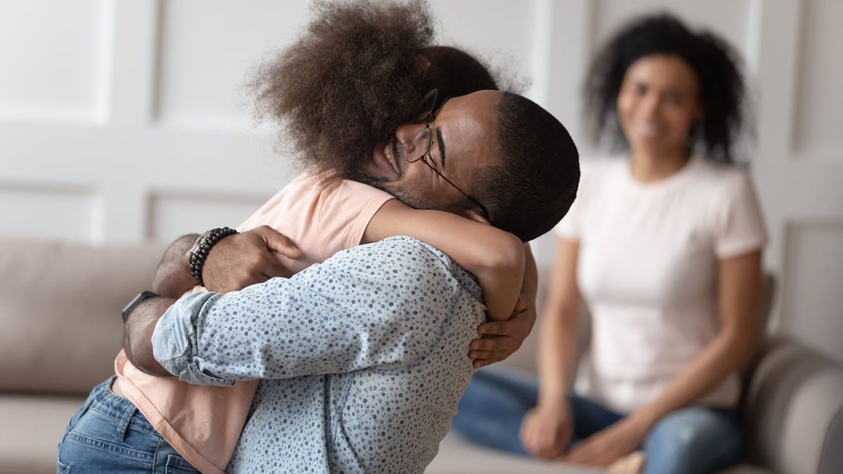 Dad hugging daughter with mom looking on