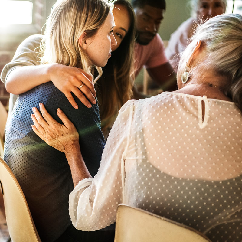women comforting a young woman in a group setting